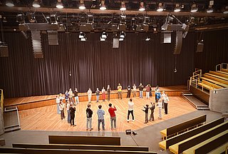 Bühne auf der ein Lehrer mit einer Schulklasse musiziert